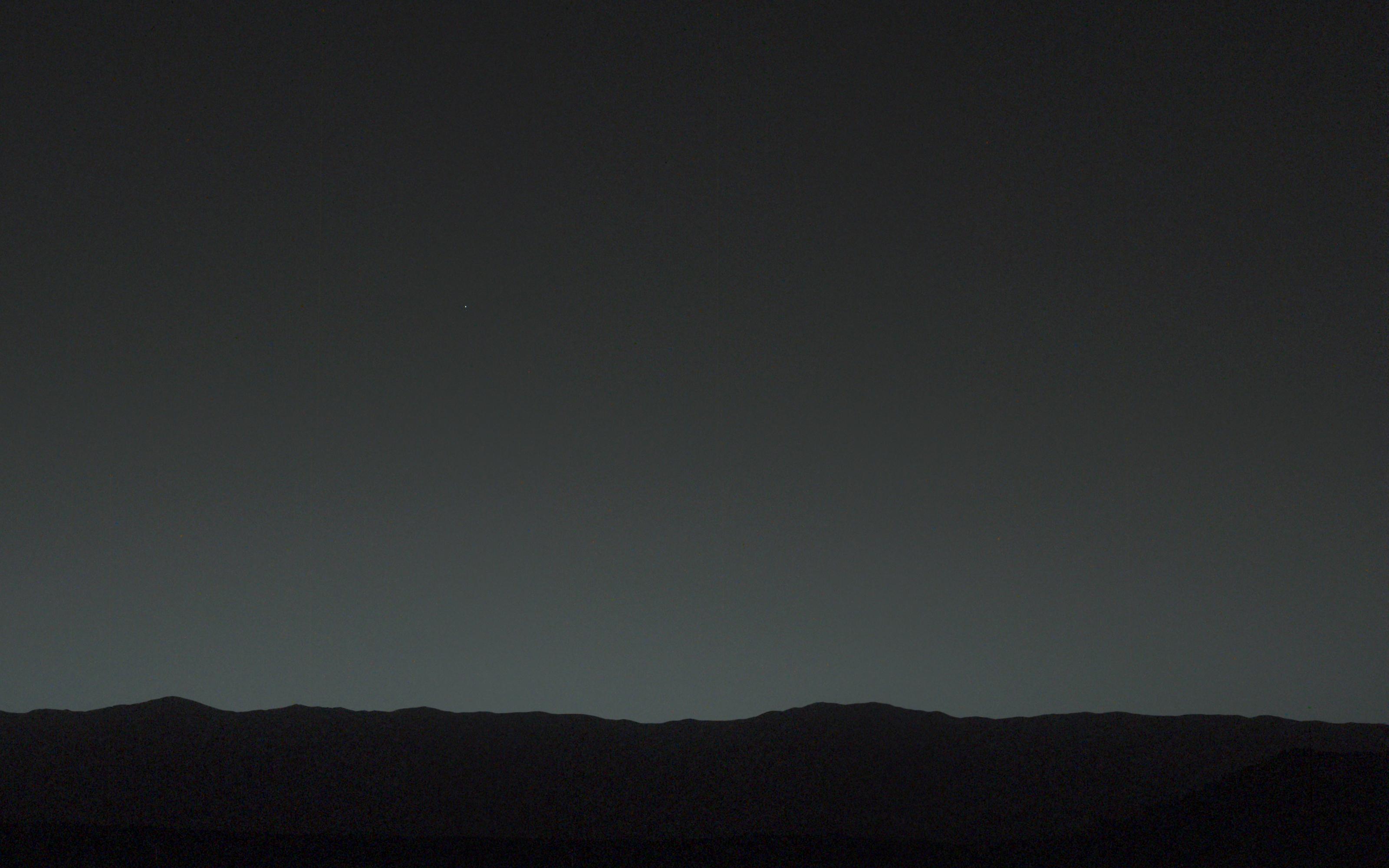 Blue sunset from Gale crater on Mars, photographed by Curiosity. The Sun is small. The sky cools toward blue.
